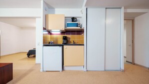 Una kitchenette compacta equipada con microondas, cafetera y un refrigerador pequeño.