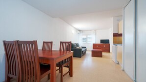 Un espacio habitable compacto con comedor, sofá, kitchenette y televisión.