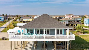 Una casa de dos pisos con balcón, terraza y vista a la playa.