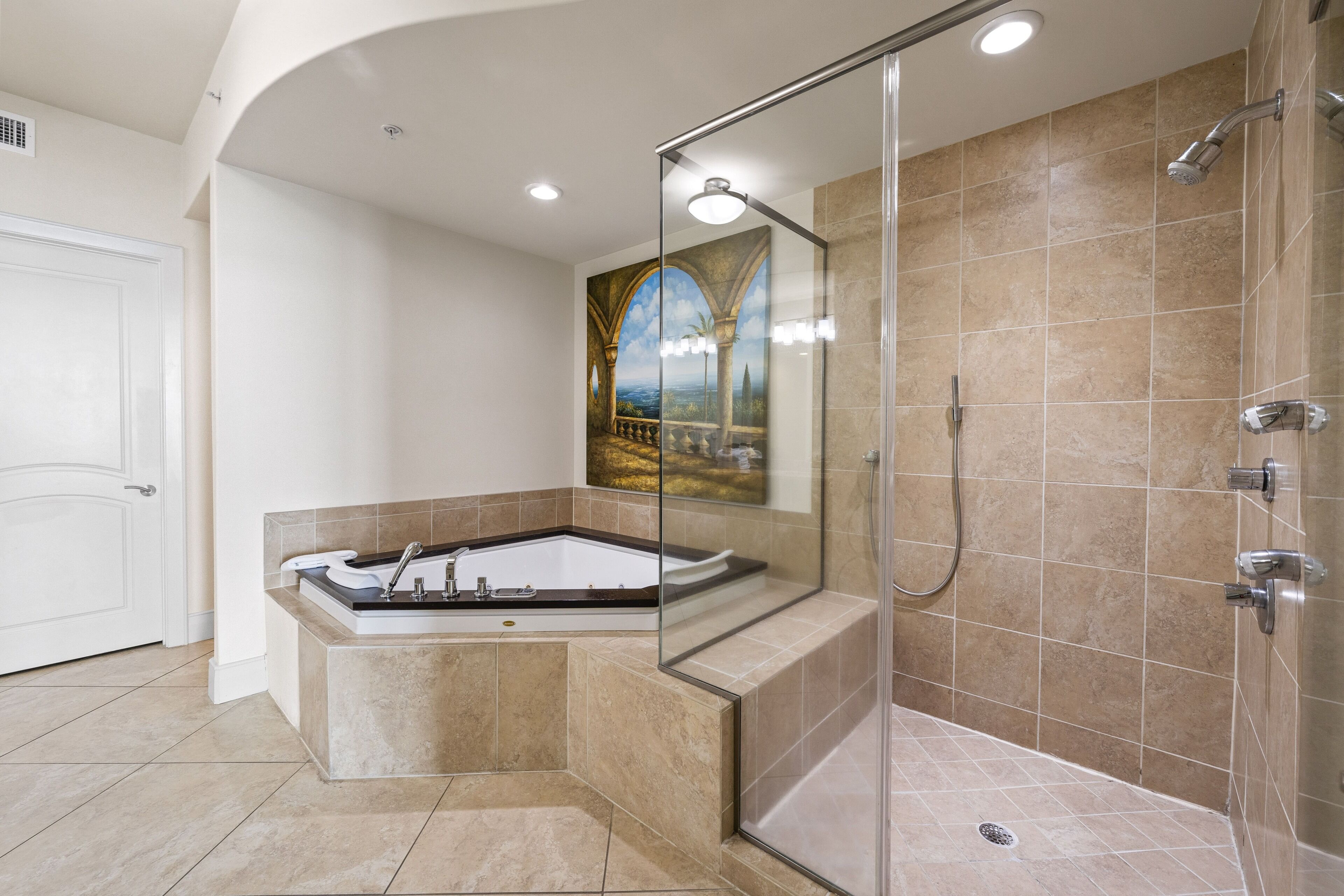 A modern bathroom with a glass-enclosed shower, a freestanding bathtub, and a large mirror reflecting a scenic painting.