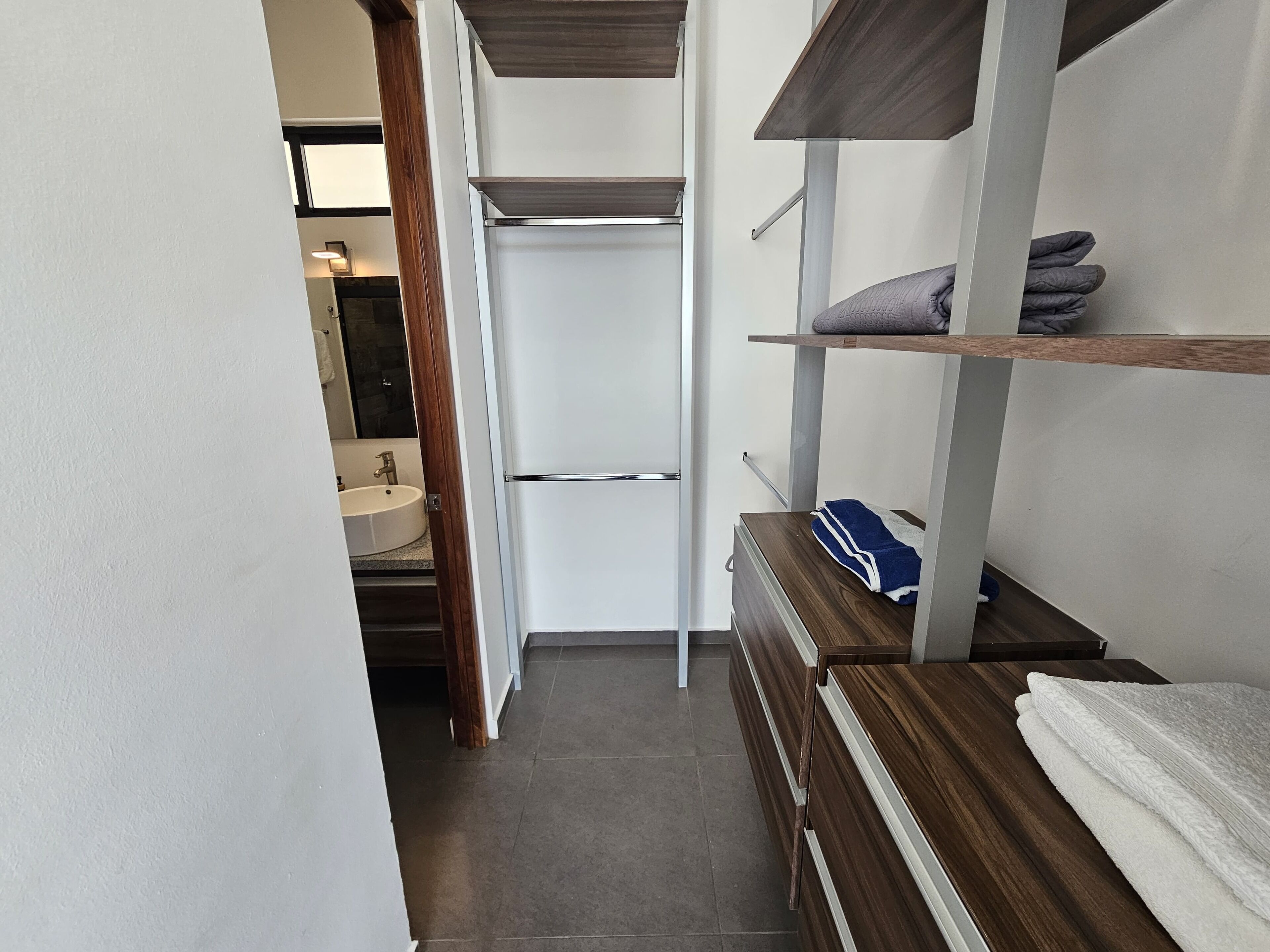 Un pasillo estrecho que conduce a un baño con lavamanos y espejo.