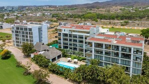 A modern hotel with multiple buildings, a swimming pool, and lush greenery. - Torres Mittah (La Cruz de Huanacaxtle)