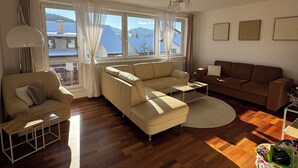 Un salon moderne avec un ensemble de canapés, une table basse et une vue sur les montagnes grâce à de grandes fenêtres.