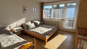 Une chambre avec deux lits, un plancher en bois, une fenêtre avec des rideaux et un ventilateur de plafond.
