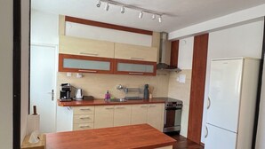 Une cuisine avec des meubles de rangement en bois, un four encastré et un réfrigérateur blanc.