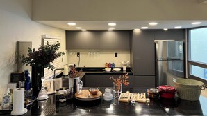 Una cocina moderna con armarios grises, un refrigerador de acero inoxidable y un ventanal que proporciona luz natural.