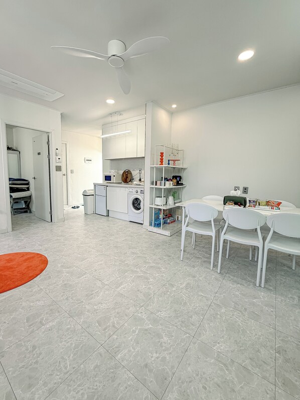Una cocina moderna con armarios blancos, una lavadora y un comedor con sillas y mesa blancos.