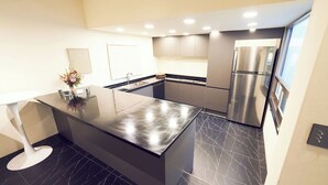 Una cocina moderna con una isla central, electrodomésticos de acero inoxidable y suelo de mármol negro.