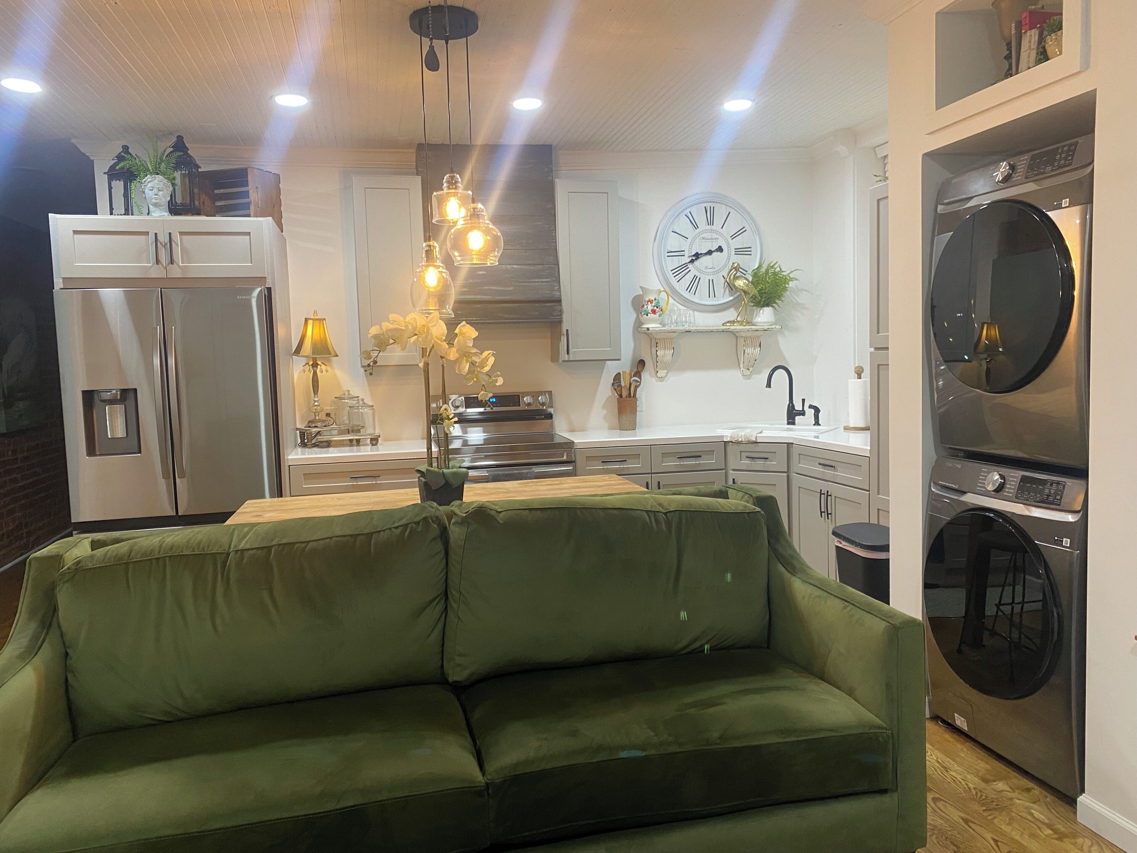 A modern kitchen with a built-in oven, a sink, and a clock on the wall.