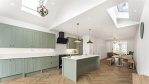 Una cocina moderna con armarios verdes, una isla central e iluminación colgante.