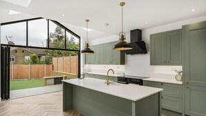 Una cocina moderna con una isla grande, armarios verdes y vistas a un patio trasero.