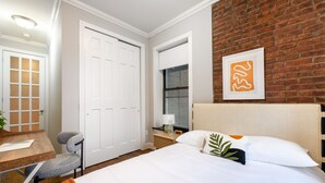 Ein Hotelzimmer mit Bett, Schreibtisch, Stuhl, Fenster und einer Ziegelwand.