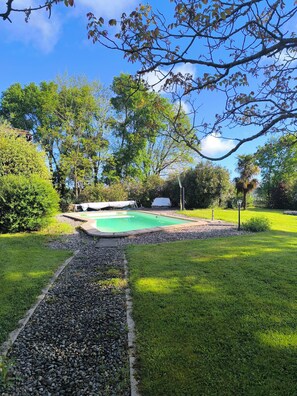 A backyard with a swimming pool, surrounded by a well-maintained lawn and various trees. - Country house for large groups Marciac festival Capacity 14 people (Castex)