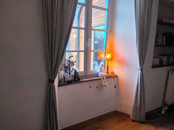 A room with a window, a lamp, a shelf with books, and a power outlet. - Country house for large groups Marciac festival Capacity 14 people (Castex)