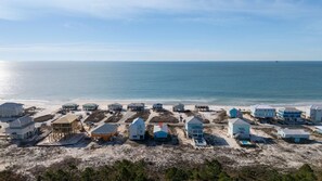 A coastal area with multiple beach houses, some with visible swimming pools, and a clear view of the ocean. - Steps From Beach | Porch Swing & Ocean Views | Sleeps 8 | Fort Morgan (Gulf Shores)