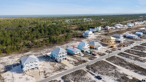 An aerial view of a coastal development with multiple buildings, including a large multi-story structure with balconies and a smaller single-story building. - Steps From Beach | Porch Swing & Ocean Views | Sleeps 8 | Fort Morgan (Gulf Shores)