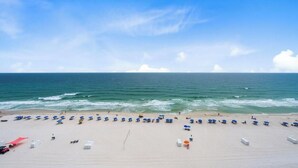 Een strand met rijen parasols en ligstoelen, een zandstrand en de oceaan op de achtergrond.