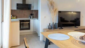 Een moderne keuken met een inbouwoven en een eetgedeelte met een houten tafel en stoelen.