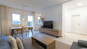Een moderne woonkamer met een bank, salontafel, televisie en een eethoek.