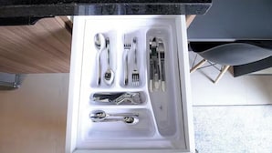 A drawer with neatly arranged cutlery including spoons, forks, knives, and a wrench. - Vn Consolação 710 (São Paulo)
