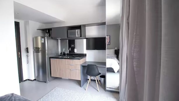 A modern, compact hotel room with a kitchenette, a bed, and a desk. - Vn Consolação 710 (São Paulo)