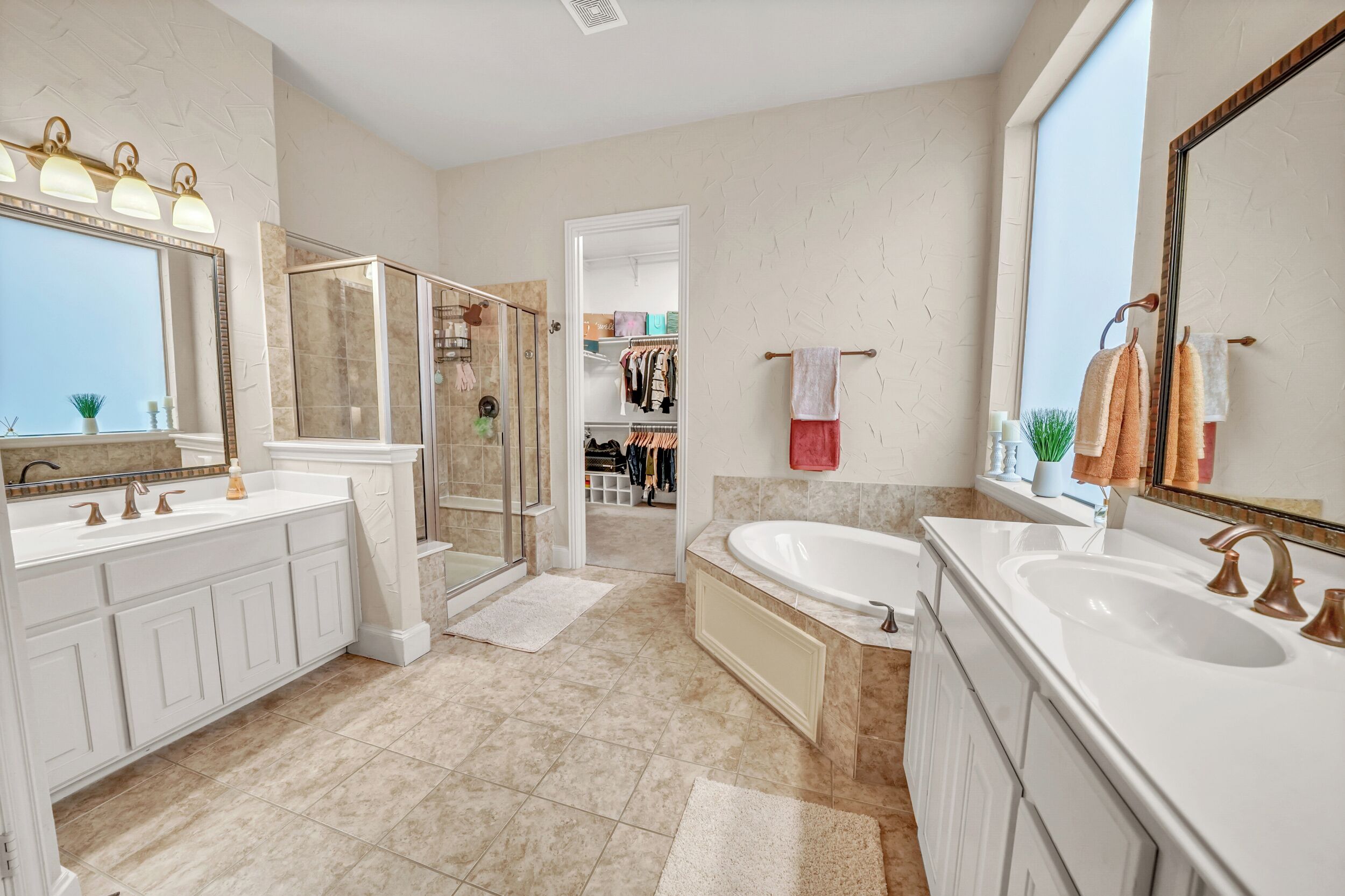 A modern bathroom with a walk-in shower, two sinks, and a large mirror.