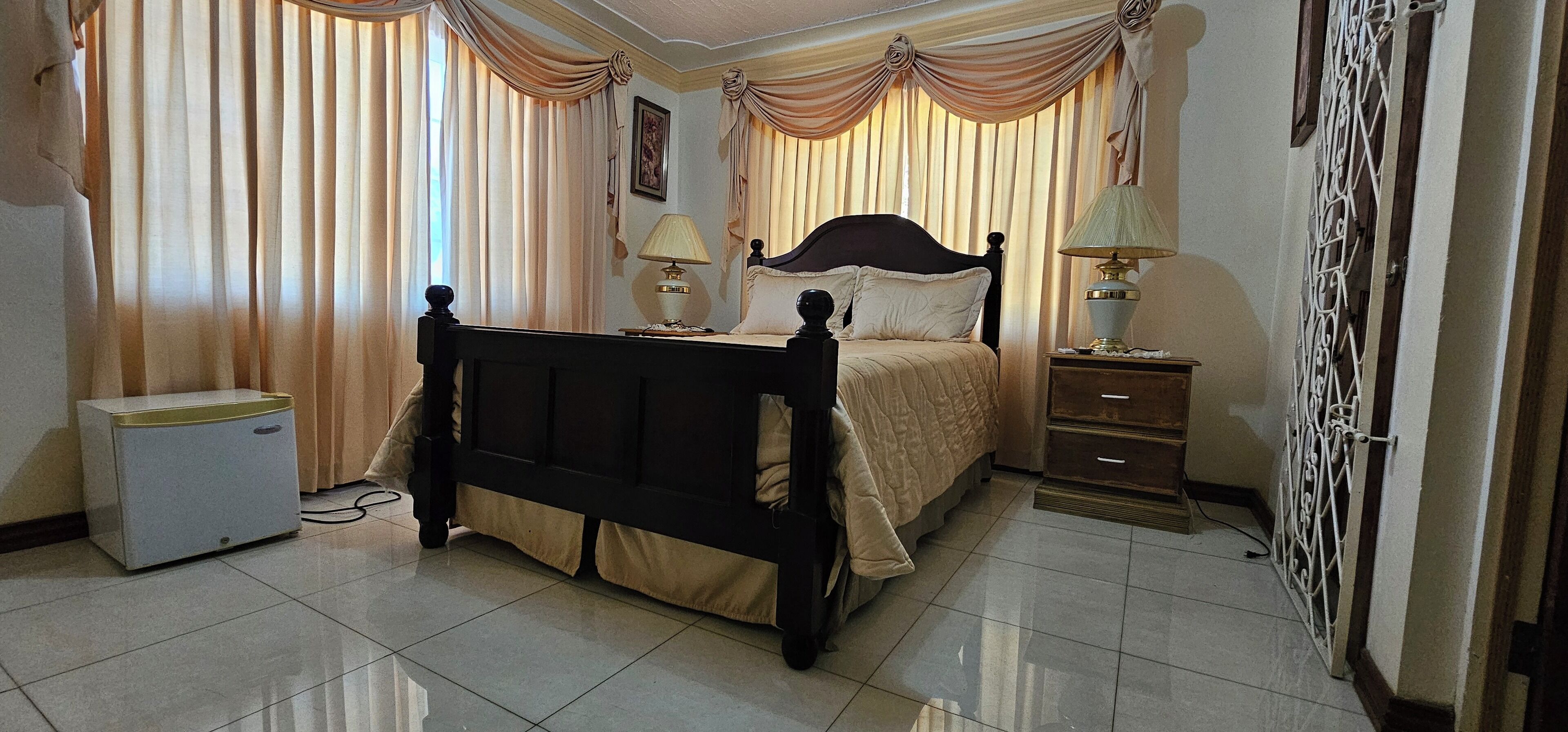 A bedroom with a bed, bedside tables, curtains, a radiator, and a wardrobe.
