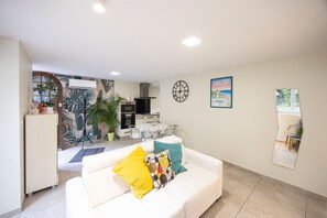 A living room with a white sofa, a clock, and a poster on the wall. - Le Victor Apartment – Comfortable Stay in Aix-les-Bains (Aix-les-Bains)