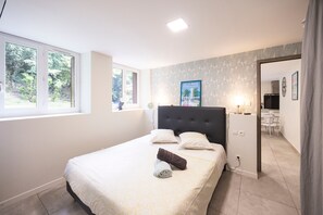 A bedroom with a bed, a nightstand, a lamp, and a poster on the wall. - Le Victor Apartment – Comfortable Stay in Aix-les-Bains (Aix-les-Bains)