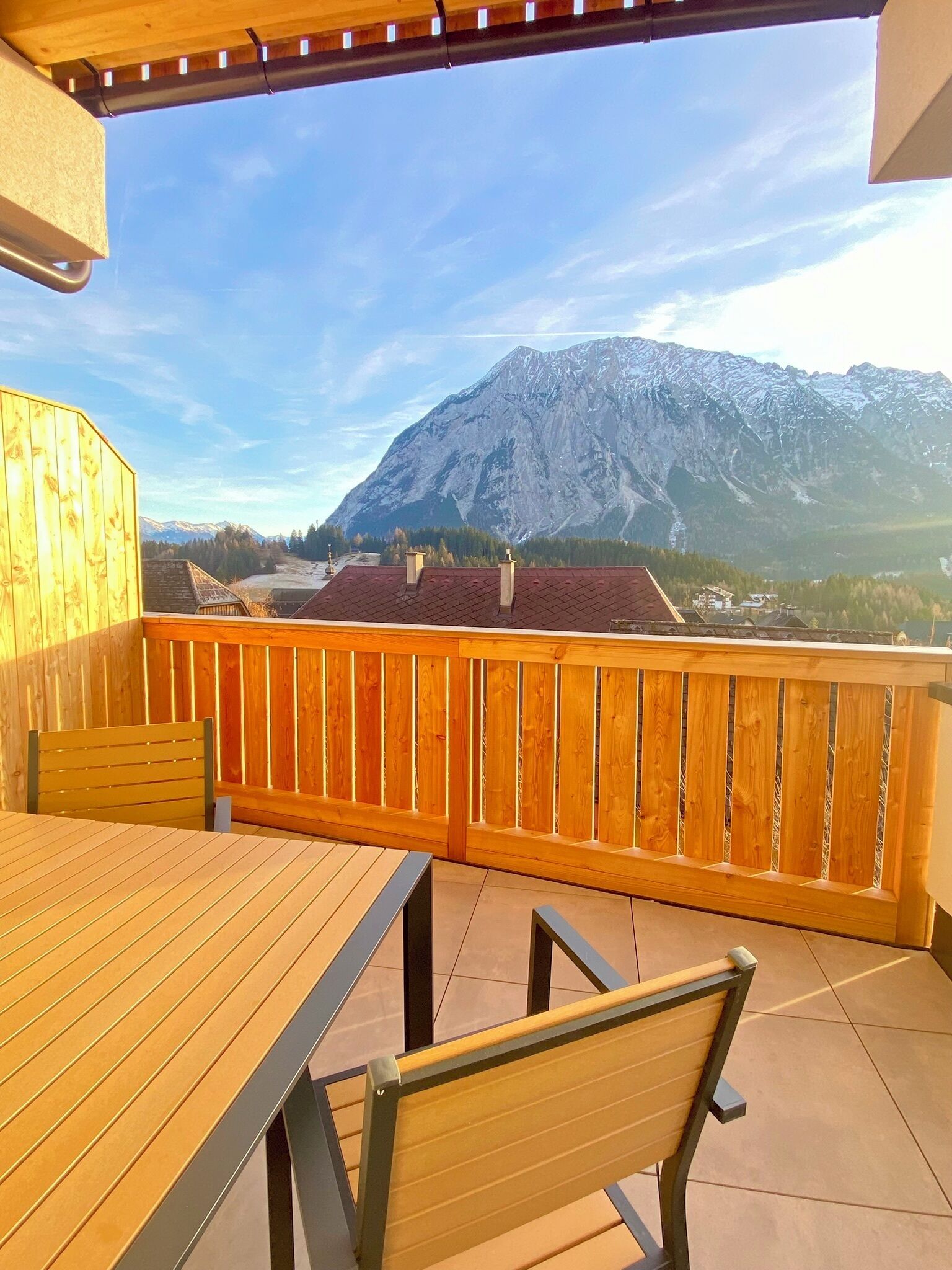 Una terraza de madera con una mesa y sillas, con vistas a la montaña.