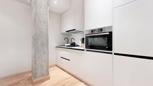 Eine moderne Küche mit weißen Schränken, einer schwarzen Arbeitsplatte und Edelstahlgeräten, darunter ein Backofen und eine Dunstabzugshaube.