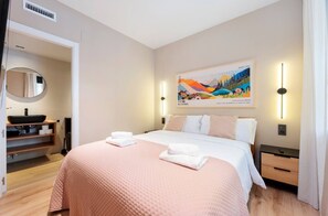 A hotel room with a bed, a bathroom with a sink, and a painting on the wall. - STAYMADRID - Chic Apartment (MADRID)