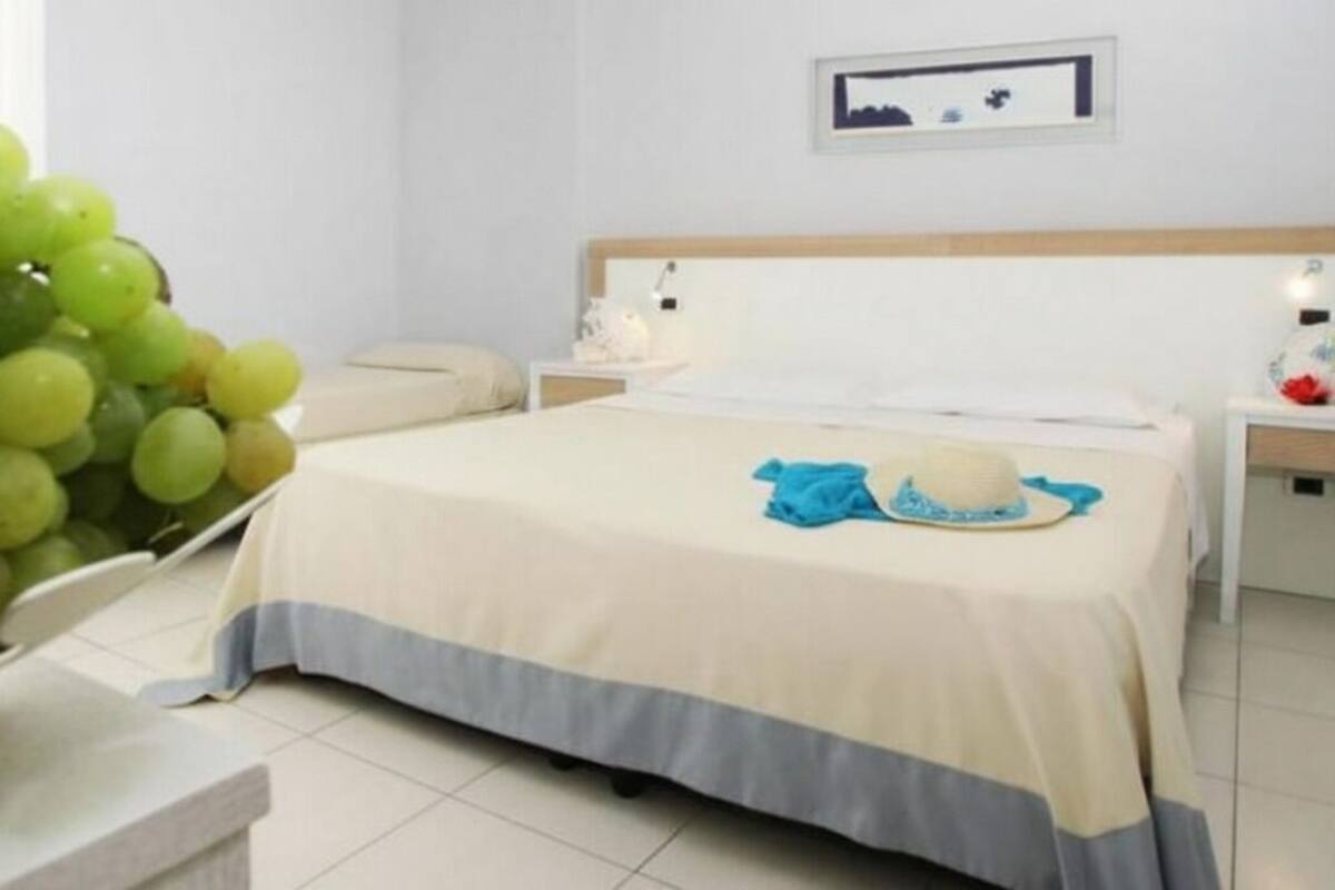 Una habitación de hotel con una cama, mesitas de noche y un cuadro colgado en la pared.