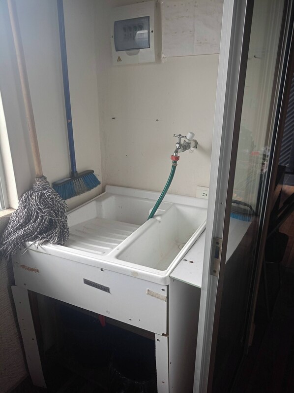 A bathroom with a sink, a mop, a broom, and a water faucet. - Encantador Apartamento Central (Dosquebradas)