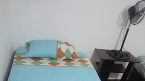 Una cama individual con una colcha estampada y una toalla enrollada.