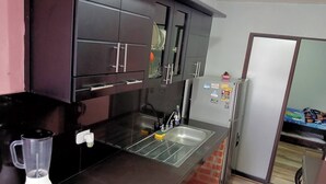 Una cocina moderna con armarios oscuros, un lavamanos de acero inoxidable y un refrigerador.