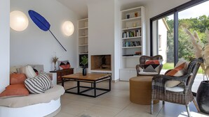 Un salon moderne comprenant un canapé, une table basse, un fauteuil en osier et une bibliothèque.