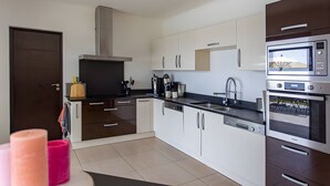 Une cuisine moderne avec des meubles blancs, des appareils en acier inoxydable et un plan de travail noir.