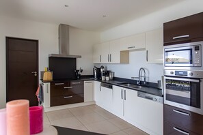 A modern kitchen with white cabinets, stainless steel appliances, and a black countertop.
