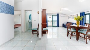 A spacious dining area with a wooden table and chairs, a blue patterned wall, and a view through a glass door. - Villa Francesco with Sea View (Orosei)
