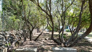A stone bench, a stone wall, and trees in a park. - Villa Francesco with Sea View (Orosei)