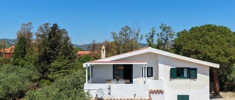 A white building with a tiled roof, a balcony, and a view of the surrounding landscape.