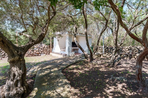 A rustic stone structure surrounded by trees, with a clear path leading to it. - Villa Francesco with Sea View (Orosei)