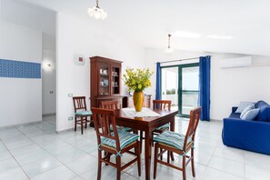 Ein Essbereich mit Tisch, Stühlen, einer Blumenvase, einem Schrank und einem blauen Sofa.