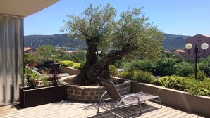 A balcony with a metal chair, a potted tree, and a view of a mountainous landscape. - Between the upper town and the marina (Porto-Vecchio)