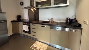 A modern kitchen with stainless steel appliances, a built-in oven, and a dishwasher. - Between the upper town and the marina (Porto-Vecchio)