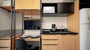 Een gezellige, kleine keuken met een magnetron, koffiezetapparaat en een klein spoelbakje.