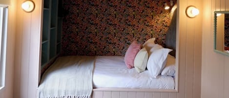 A cozy bedroom with a built-in bed, a small wooden table, and a chair.