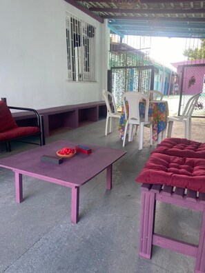 Un espace extérieur abrité, aménagé avec une table, des chaises et un banc.