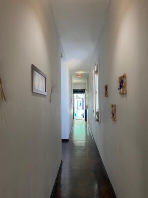 A hallway with white walls, framed pictures, and a wooden floor. - Açaizeiro Hostel (Belém)